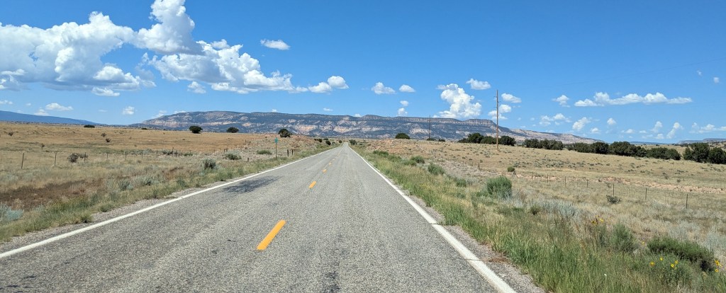 a road, a field, and blue sky